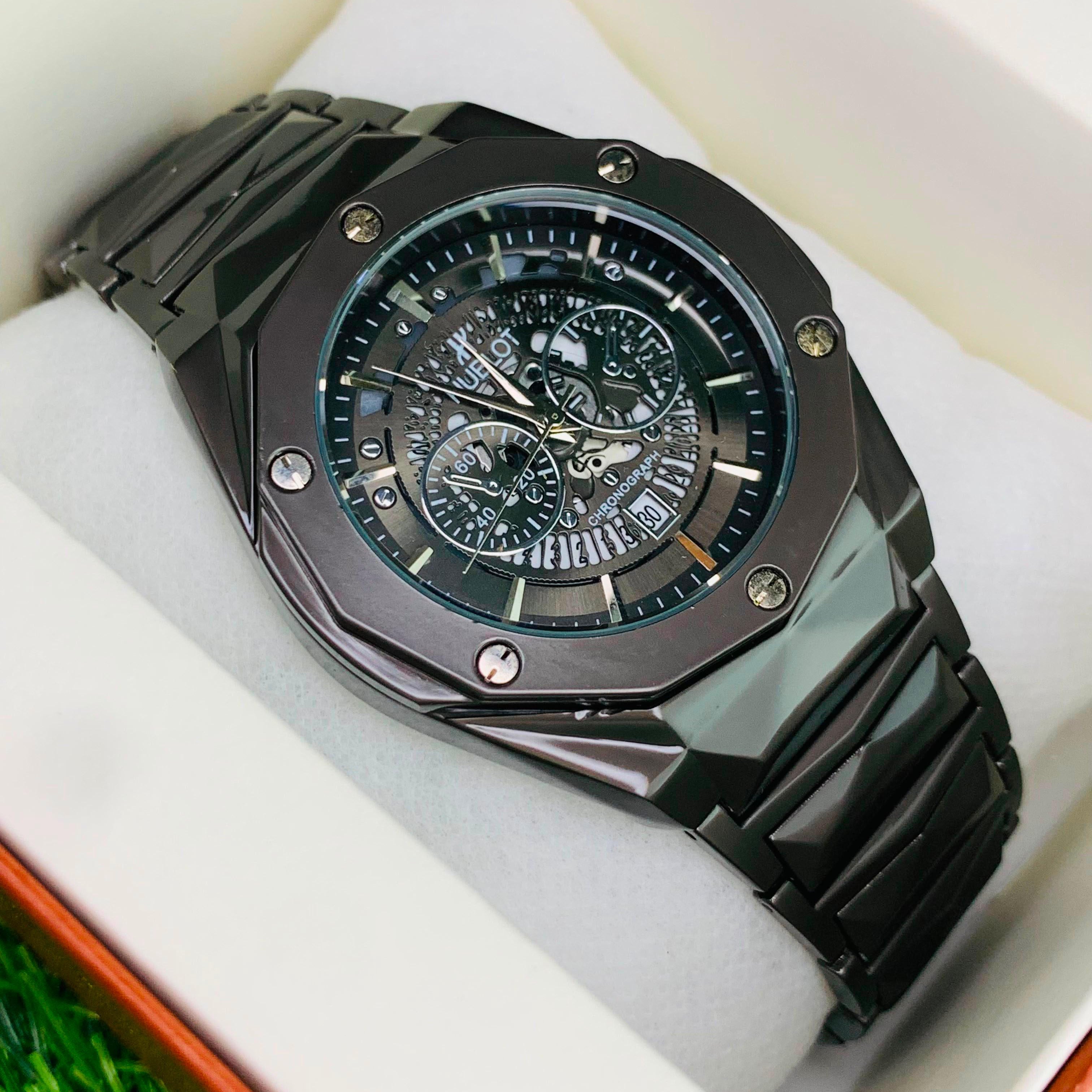 Black wristwatch with detailed face in a box on grass