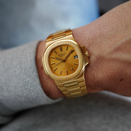 Gold wristwatch on a person's wrist with a blurred background