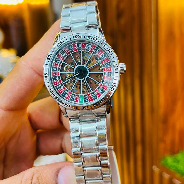 Silver watch with a unique face held by a hand against a blurred background