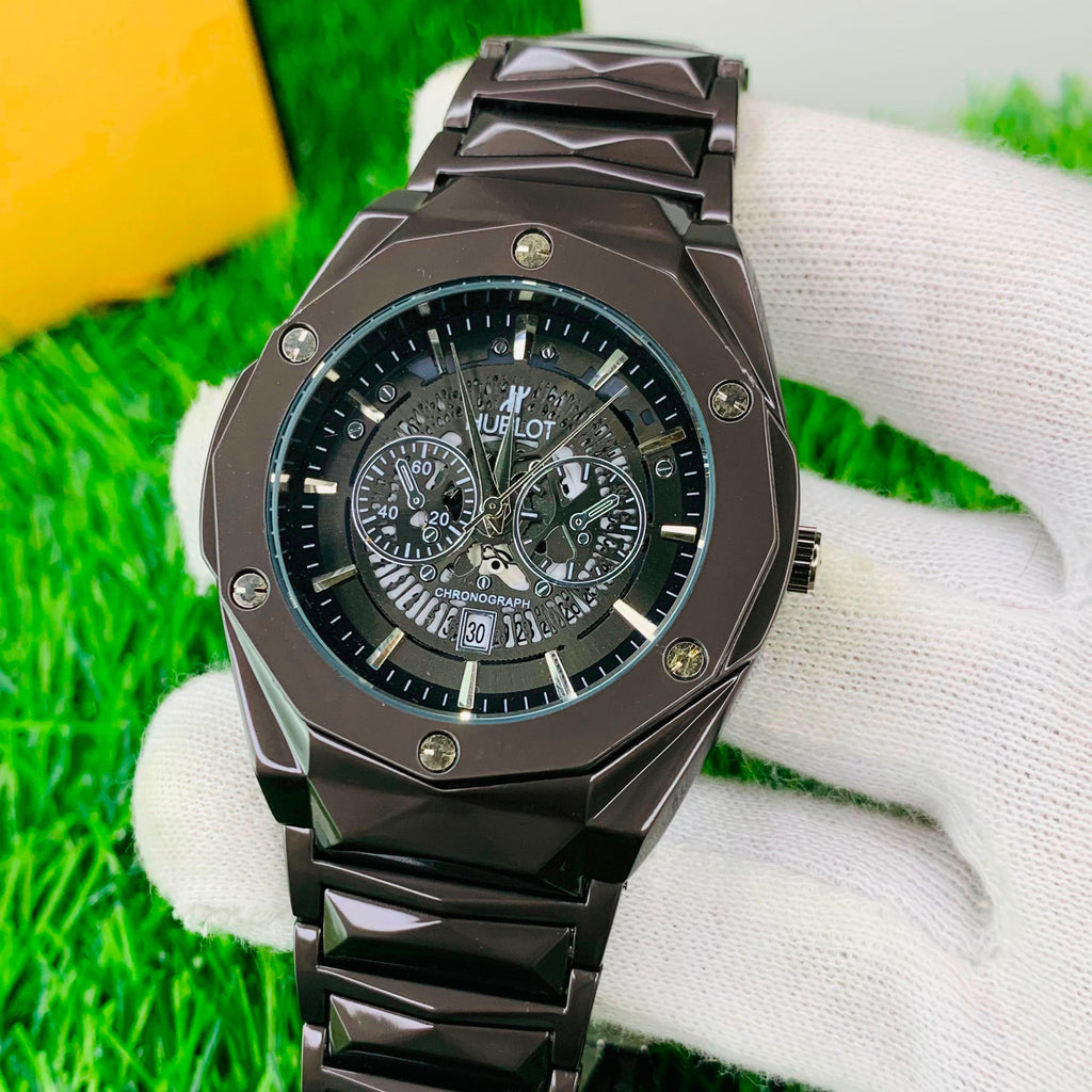 Black Hublot watch on a white glove with grass background