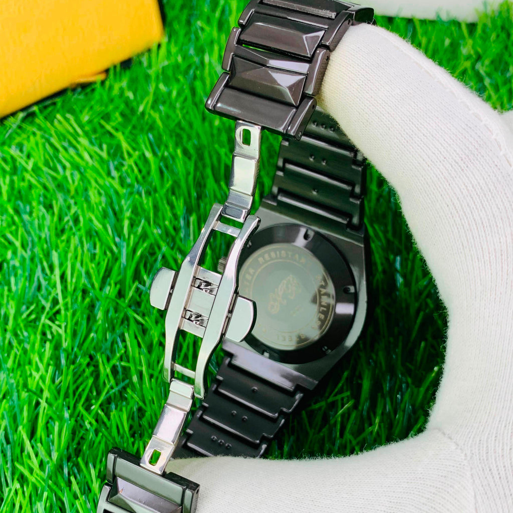 Silver watch with black band on a white gloved hand against a grass background
