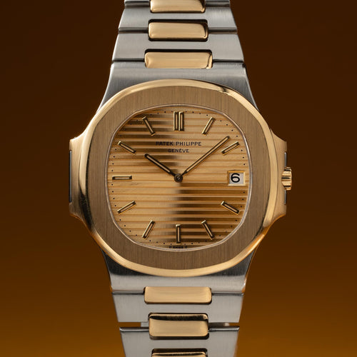 Luxury watch with gold and silver band on a gradient brown background